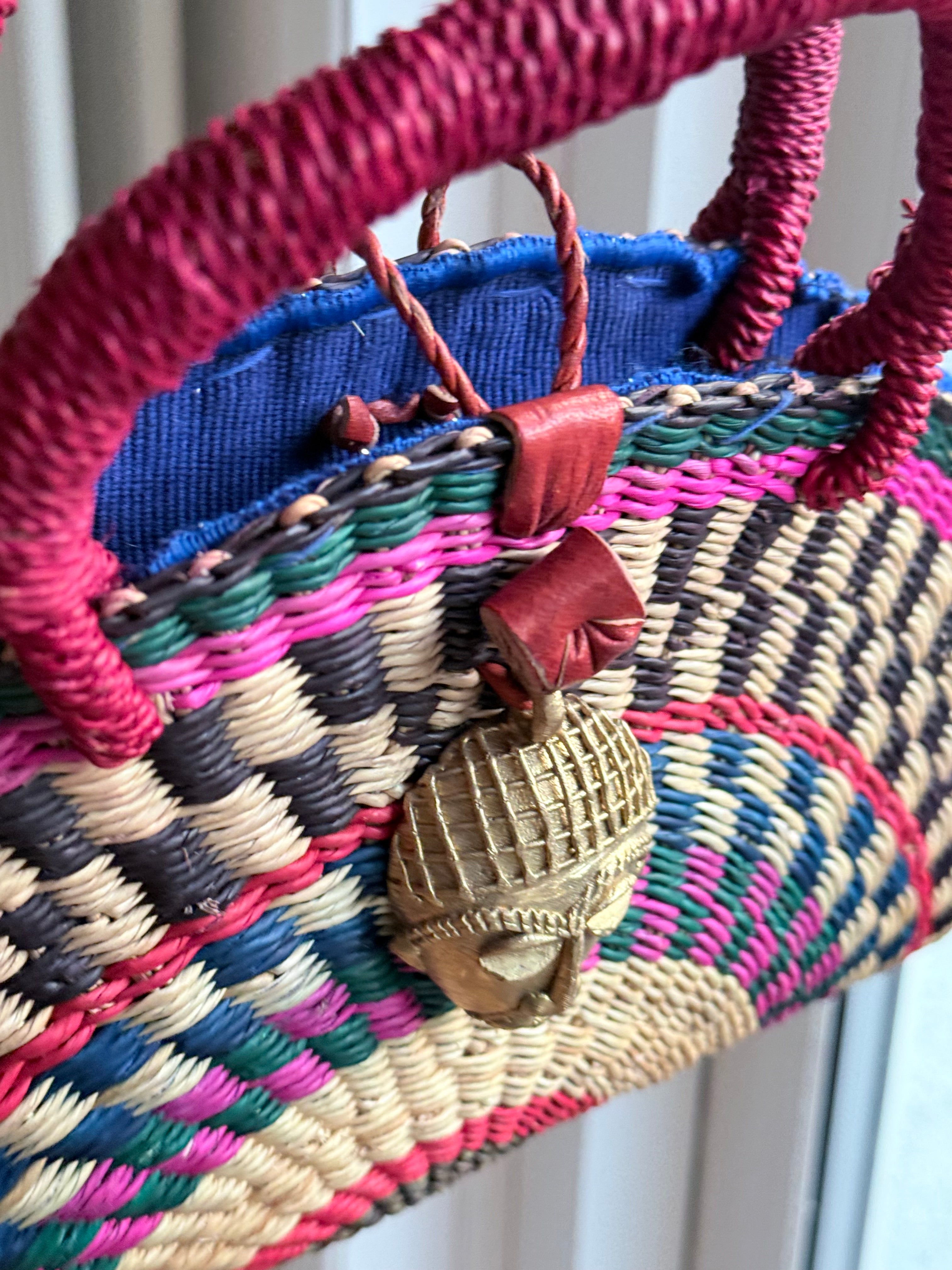 African Handwoven Half-Moon Bag with Brass Mask Pendant & Red Handles